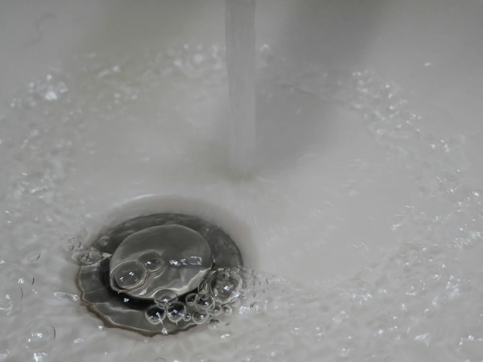 Water flowing freely and smoothly down a clean residential sink drain